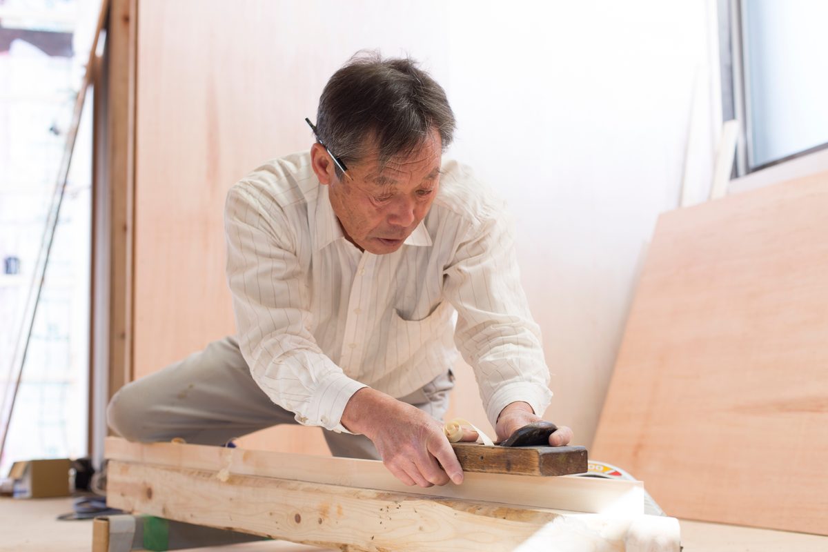 鉋で木材を仕上げる熟練の大工